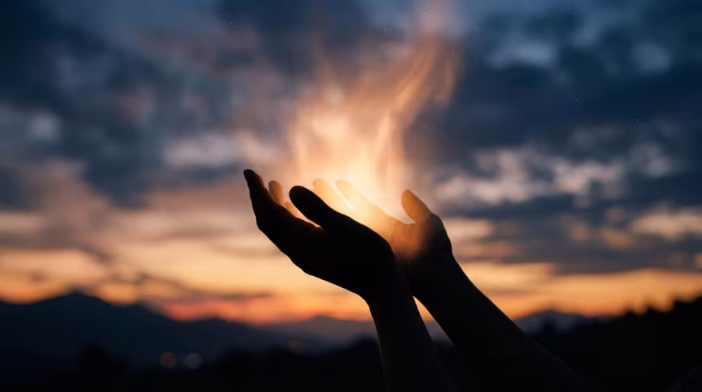 Silueta de manos abiertas liberando una luz espiritual brillante que simboliza el perdón y la sanación del alma.